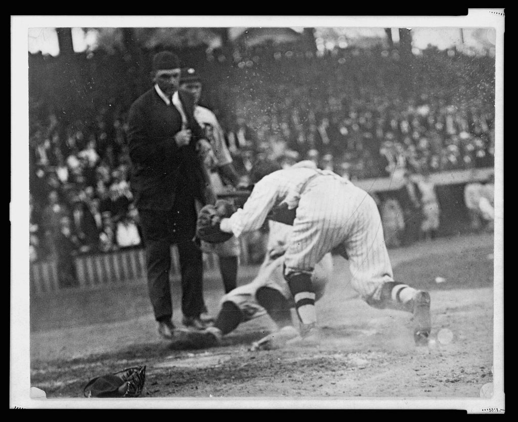 Vintage photo of a catcher tagging a runner sliding into home plate as the umpire watches